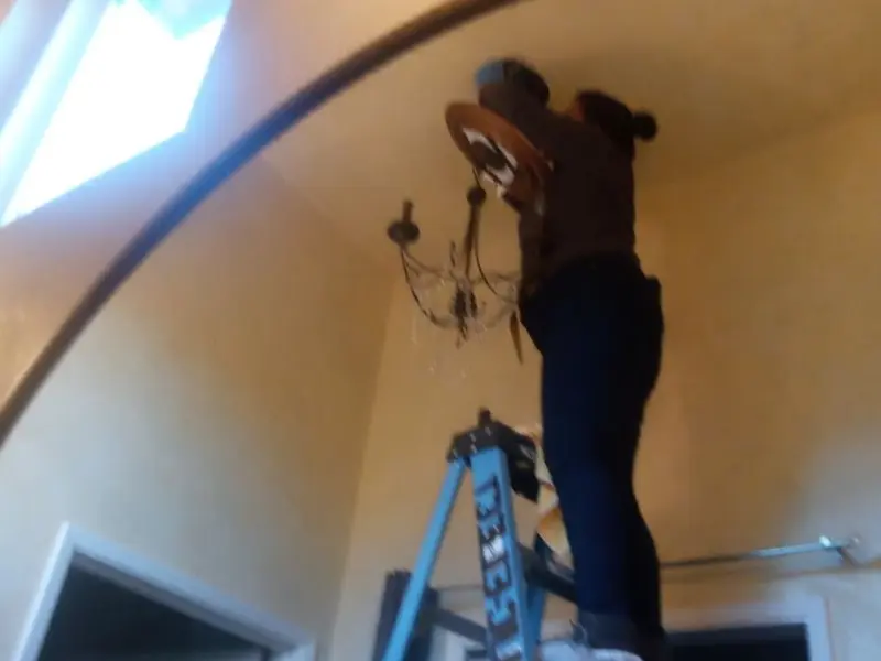 Electrician installing a chandelier in a Willis residence